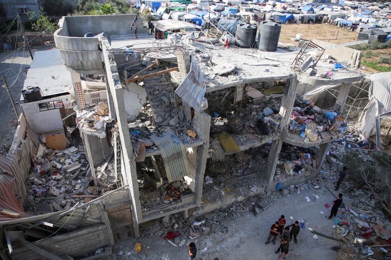 &copy; Reuters. Des personnes se tiennent à côté d'une maison endommagée par une frappe israélienne, dans le cadre du conflit actuel entre Israël et le groupe islamiste palestinien Hamas, à Rafah, dans le sud de la bande de Gaza. /Photo prise le 3 mai 2024/REUTERS