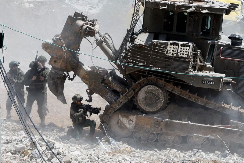 &copy; Reuters. Varios soldados israelés se cubren tras un bulldozer militar durante una incursión en la localidad de Deir al-Ghusun, Cisjordania. 4 mayo 2024. REUTERS/Raneen Sawafta