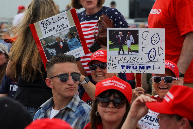© Reuters. Trump supporters hold signs as they attend a campaign rally in Wilmington, North Carolina. April 20, 2024. REUTERS/Brian Snyder