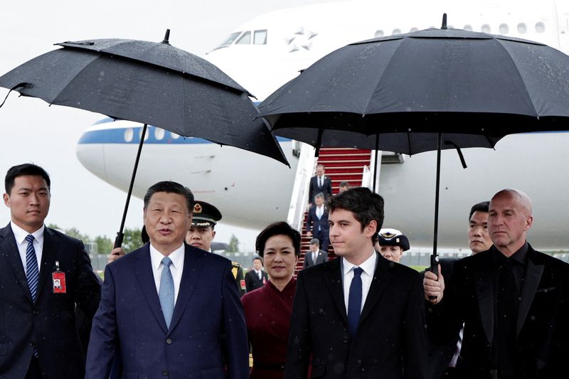 © Reuters. France's Prime Minister Gabriel Attal, China's President Xi Jinping and his wife Peng Liyuan walk under umbrellas upon their arrival for an official two-day state visit, at Orly airport, south of Paris on May 5, 2024. Chinese President Xi Jinping arrived in France on May 5, 2024, for a state visit hosted by Emmanuel Macron where the French leader will seek to push his counterpart on issues ranging from Ukraine to trade.     STEPHANE DE SAKUTIN/Pool via REUTERS