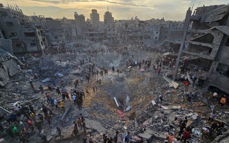 &copy; Reuters. Palestinos buscan víctimas en medio de profundos cráteres llenos de hormigón roto y metal retorcido, tras los ataques aéreos israelíes contra el campo de refugiados de Yabalia, en el norte de la Franja de Gaza
Oct 31, 2023.   
REUTERS/Anas al-Shareef