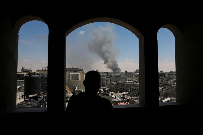 &copy; Reuters. فلسطيني ينظر إلى دخان يتصاعد بعد هجوم إسرائيلي بينما تشن القوات الإسرائيلية عملية برية وجوية في الجزء الشرقي من رفح جنوب قطاع غزة يوم الساب