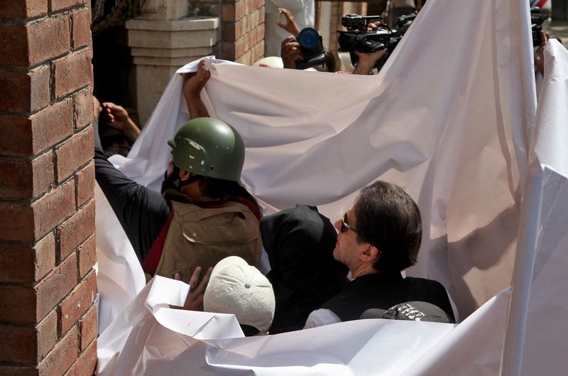 &copy; Reuters. رئيس الوزراء الباكستاني السابق عمران خان وزجته بشرى بيبي تغطيهم ملاءة بيضاء لدى وصولهم للمثول أمام المحكمة العليا في لاهور بباكستان يوم 15 م