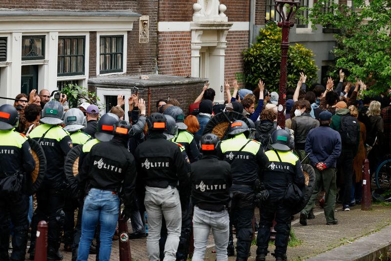&copy; Reuters. Police officers stand next to pro-Palestinian protesters blocking the way at the University of Amsterdam during a protest against the ongoing conflict between Israel and the Palestinian Islamist group Hamas in Gaza, in Amsterdam, Netherlands, May 8 2024. 