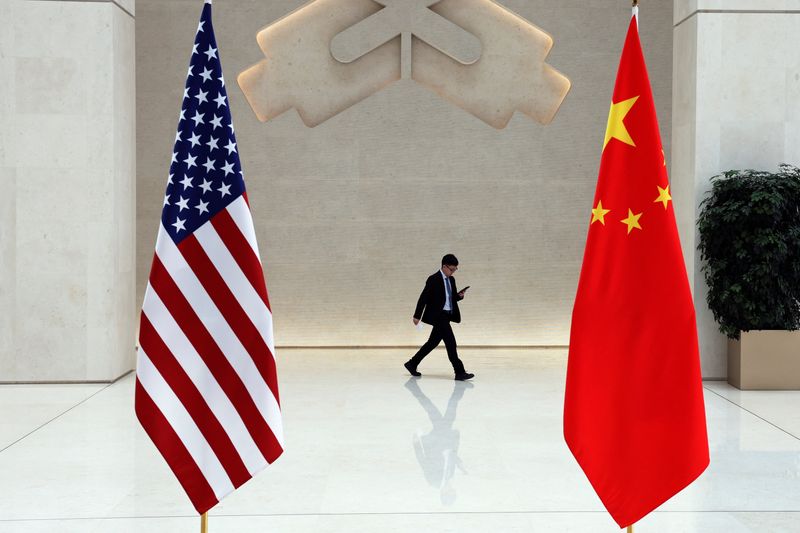 &copy; Reuters. Un hombre camina junto a banderas estadounidenses y chinas el día de la reunión entre la secretaria del Tesoro estadounidense, Janet Yellen, y el gobernador del Banco Popular de China (PBOC), Pan Gongsheng, en Pekín, China, el 8 de abril de 2024. REUTE