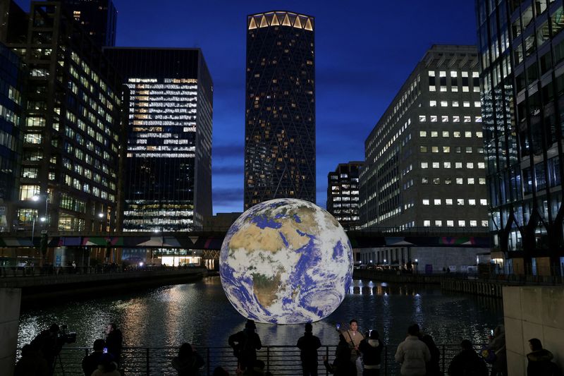 &copy; Reuters. FILE PHOTO: People look at Luke Jerram's 'Floating Earth', an installation as part of the Canary Wharf Winter Lights festival in the financial district in London, Britain, January 17, 2023. REUTERS/Kevin Coombs/File Photo