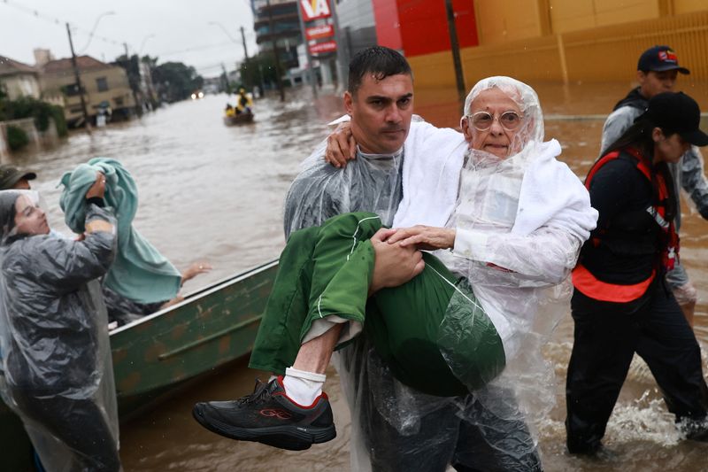 © Reuters. A volunteer carries a man, who has been evacuated from a flooded area in Porto Alegre, Rio Grande do Sul state, Brazil May 10, 2024. REUTERS/Diego Vara