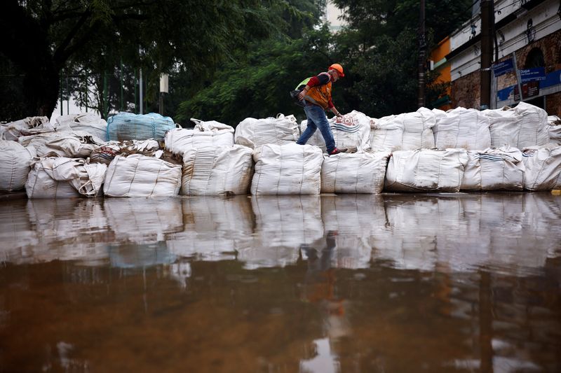 &copy; Reuters. Homem caminha sobre sacos colocados para conter as águas das enchentes em Porto Alegre
12/05/2024 REUTERS/Amanda Perobelli
