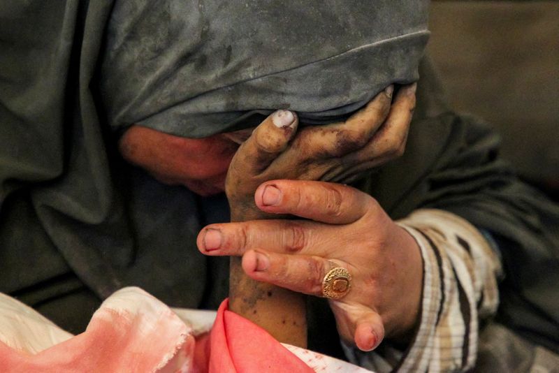 &copy; Reuters. A mulher palestina Buthayna Abu Jazar segura a mão de seu filho Hazma, morto em um ataque israelense, em meio ao conflito em curso entre Israel e o Hamas, em Rafah, no sul da Faixa de Gaza.
09/05/2024
REUTERS/Hatem Khaled    