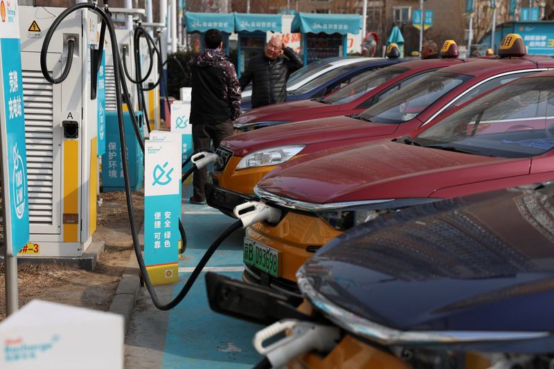 &copy; Reuters. Drivers chat next to taxis charging at a Shell electric vehicle (EV) charging station in Beijing, China February 2, 2024. REUTERS/Florence Lo/File Photo