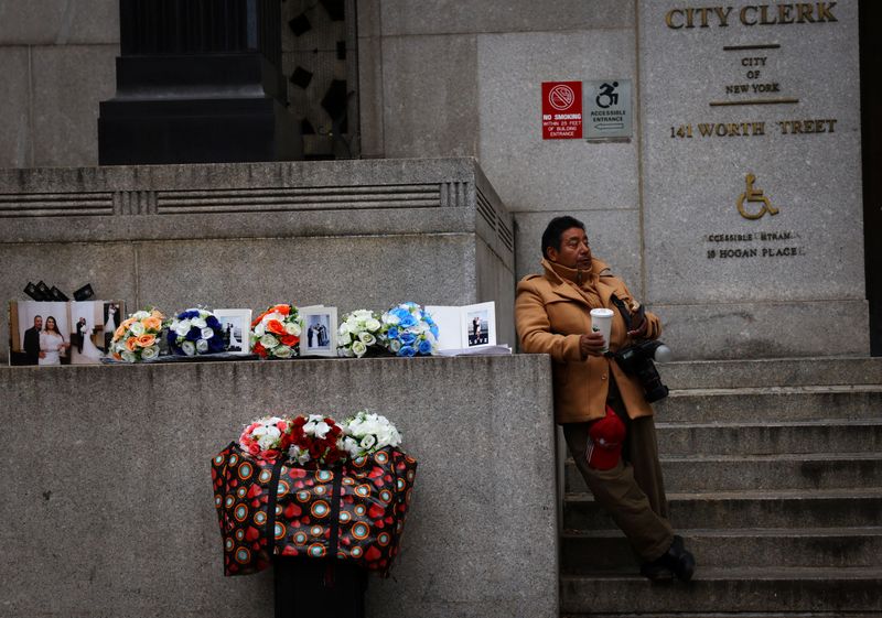 © Reuters. A photographer hoping to sell pictures to newlyweds waits outside the office of the New York City City Clerk, where couples are married in civil ceremonies, in lower Manhattan, New York, U.S., March 23, 2023. REUTERS Mike Segar/File Photo