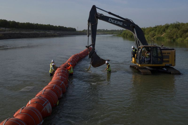 &copy; Reuters. FILE PHOTO: Workers assemble a string of buoys, to deter migrants from crossing the Rio Grande river, at the international border with Mexico in Eagle Pass, Texas, U.S. July 27, 2023.  REUTERS/Adrees Latif/File Photo