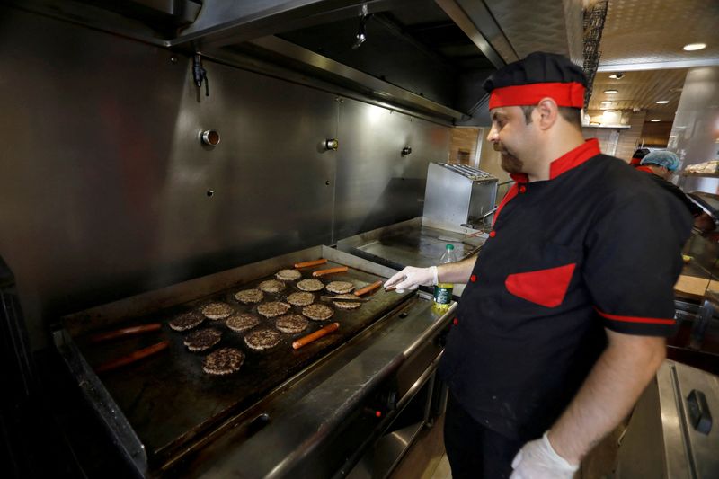 &copy; Reuters. FILE PHOTO: A man cooks burgers on the grill inside a restaurant in Baghdad, Iraq, June 25, 2019. REUTERS/Khalid al-Mousily/File Photo