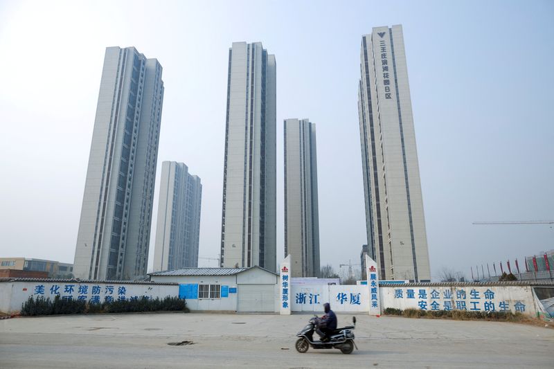 &copy; Reuters. FILE PHOTO: A man rides a scooter past apartment highrises that are under construction near the new stadium in Zhengzhou, Henan province, China, January 19, 2019. REUTERS/Thomas Peter/File Photo