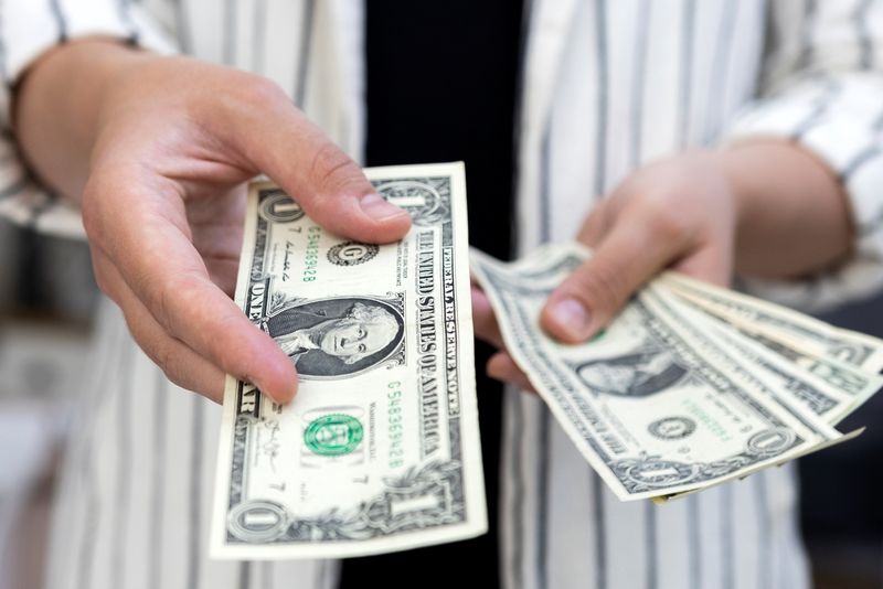 &copy; Reuters. Una donna tiene in mano delle banconote di un dollaro in questa illustrazione del 30 maggio 2022. REUTERS/Dado Ruvic