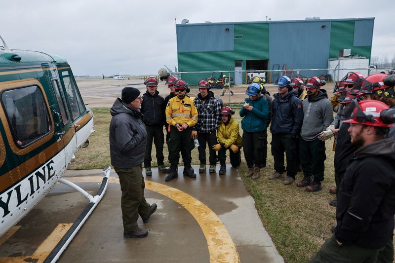 &copy; Reuters. FILE PHOTO: Alberta wildfire crews get a safety briefing from pilot Wayne Goodridge before loading into a helicopter to fly to the fire line two days after a wildfire caused the evacuation of communities on the southern edge of Fort McMurray, Alberta, Can