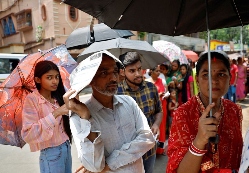 &copy; Reuters. A man uses a newspaper as others use umbrellas to protect themselves from the heat as they wait to vote outside a polling station during the fifth phase of India’s general election in Howrah district of the eastern state of West Bengal, India, May 20, 2