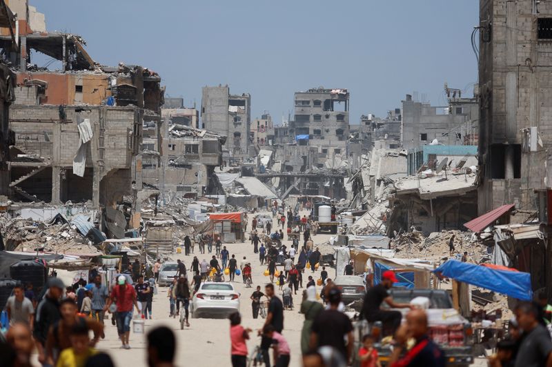 &copy; Reuters. FILE PHOTO: People and vehicles pass by buildings destroyed in an Israeli strike, amid the ongoing conflict between Israel and Hamas, in Khan Younis, in the southern Gaza Strip, May 22, 2024. REUTERS/Mohammed Salem/File Photo