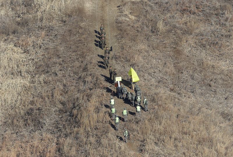 &copy; Reuters. FILE PHOTO: North Korean army soldiers, top, head to cross the Military Demarcation Line inside the Demilitarized Zone (DMZ) to inspect the dismantled South Korean guard post as South Korean army soldiers watch in the central section of the inter-Korean b