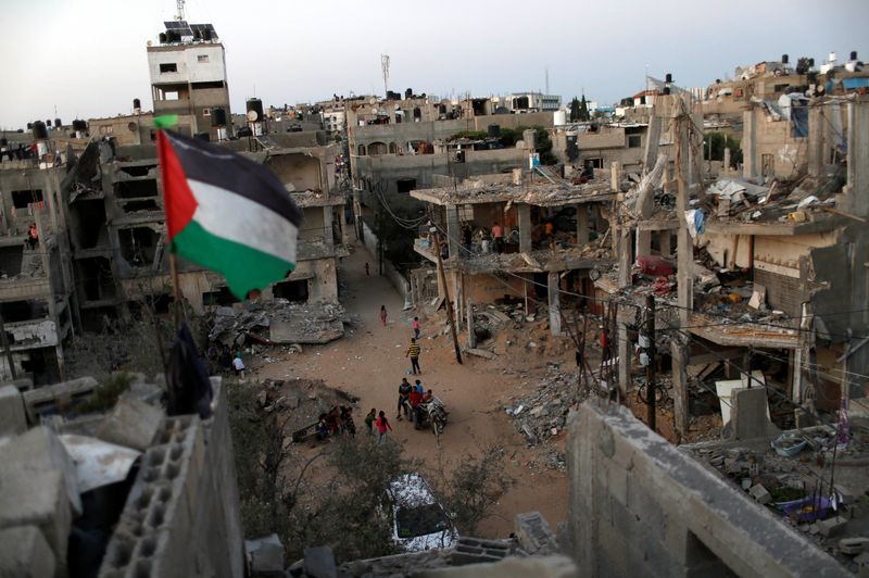 &copy; Reuters. FILE PHOTO: A Palestinian flag flies as the ruins of houses, which were destroyed by Israeli air strikes during the Israeli-Palestinian fighting, are seen, in Gaza Strip, May 25, 2021. Picture taken May 25, 2021. REUTERS/Mohammed Salem/File Photo
