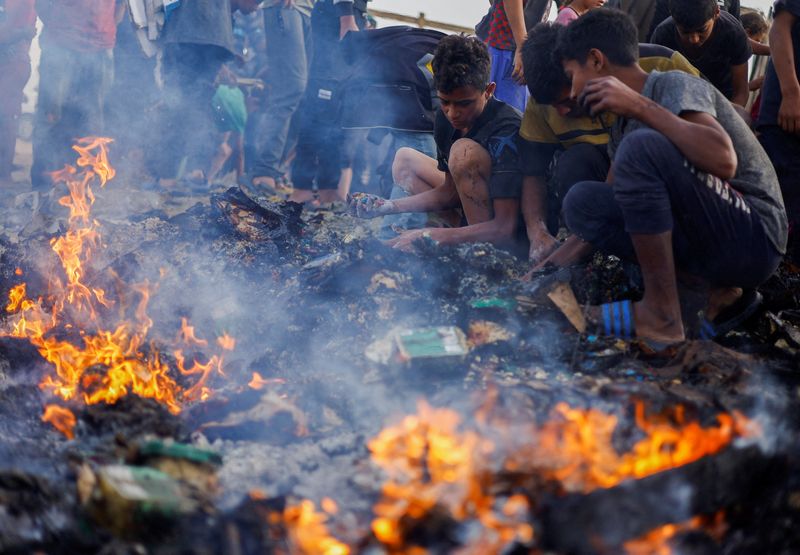 &copy; Reuters. Palestinesi cercano cibo tra i detriti bruciati all'indomani di un attacco israeliano contro un'area destinata agli sfollati, a Rafah, nel sud della Striscia di Gaza, 27 maggio 2024. REUTERS/Mohammed Salem