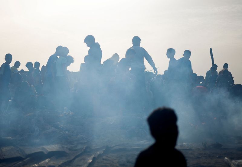 © Reuters. Palestinians search for food among burnt debris in the aftermath of an Israeli strike on an area designated for displaced people, in Rafah in the southern Gaza Strip, May 27, 2024. REUTERS/Mohammed Salem