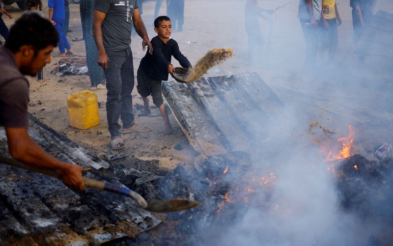 © Reuters. Palestinians put out a fire at the site of an Israeli strike on an area designated for displaced people, in Rafah, in the southern Gaza Strip, May 27, 2024. REUTERS/Mohammed Salem