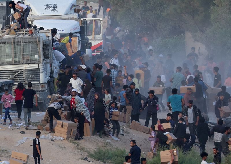 © Reuters. FILE PHOTO: Palestinians climb onto trucks to grab aid that was delivered into Gaza through a U.S.-built pier, amid the ongoing conflict between Israel and the Palestinian Islamist group Hamas, as seen from central Gaza Strip, May 18, 2024. REUTERS/Ramadan Abed/File Photo