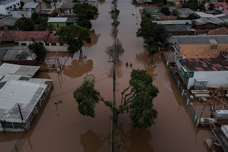 © Reuters. A drone view shows people walking on a flooded street in Eldorado do Sul, Rio Grande do Sul state, Brazil, May 10, 2024. Record-breaking floods in southern Brazil, the result of weather patterns intensified by climate change, have only started to recede after displacing half a million people in the state of Rio Grande do Sul and killing more than 160. REUTERS/Amanda Perobelli