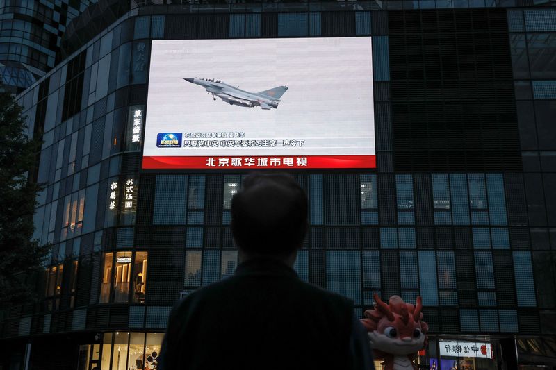 © Reuters. FILE PHOTO: A man looks at a giant screen showing news footage of military drills conducted in areas around the island of Taiwan by the Eastern Theatre Command of the Chinese People's Liberation Army (PLA), in Beijing, China May 24, 2024. REUTERS/Tingshu Wang/File Photo