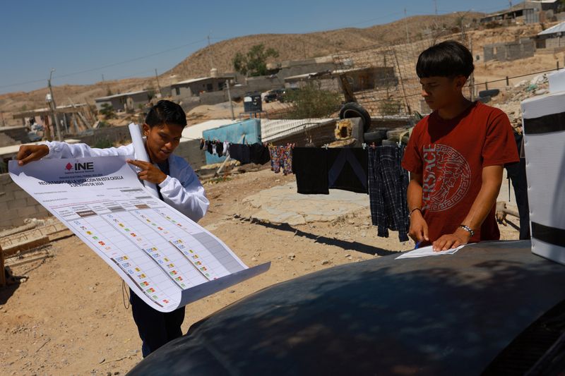 © Reuters. Eugenio Ramirez, a worker at the National Electoral Institute (INE), delivers an electoral package to a man who has been selected to act as president of a polling station for the upcoming June 2 elections, in Ciudad Juarez, Mexico May 29, 2024. REUTERS/Jose Luis Gonzalez/ File Photo