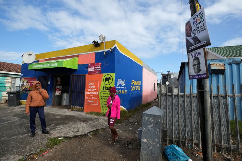 © Reuters. A woman walks past election campaign posters, next to a polling station a day after voting in the South African elections in Masiphumelele, Cape Town, South Africa May 30, 2024. REUTERS/Nic Bothma 
