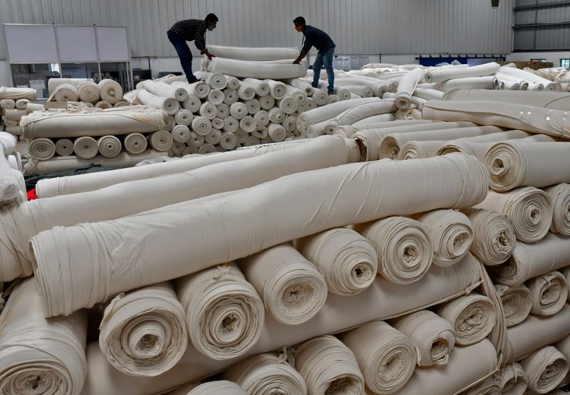 © Reuters. FILE PHOTO: Workers stack cotton fabric rolls at a textile factory of Texport Industries in Hindupur town in the southern state of Andhra Pradesh, India, February 9, 2022. Picture taken February 9, 2022. REUTERS/Samuel Rajkumar/File Photo