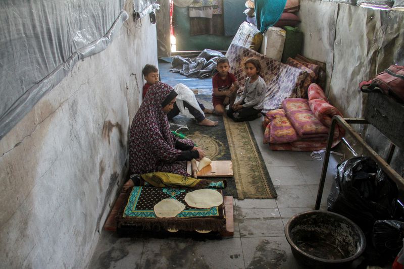 © Reuters. Displaced Palestinian woman Umm Muhammad Khrouat prepares the dough before baking bread at a school she returned to with her family, after the school was badly damaged in an Israeli raid, in Jabalia refugee camp in the northern Gaza Strip, June 2, 2024. REUTERS/Mahmoud Issa