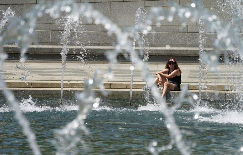 © Reuters. FILE PHOTO: A woman wearing a stars and stripes visor dips her foot into the cool fountain at the World War II Memorial on a possible record setting heat day in Washington, U.S., April 29, 2024.  REUTERS/Kevin Lamarque/File Photo