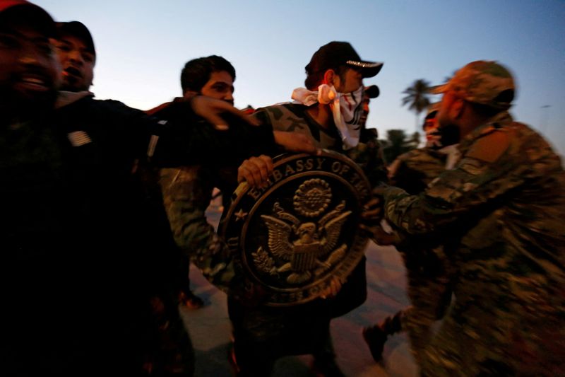 © Reuters. FILE PHOTO: Protesters and militia fighters carry the logo of the U.S. Embassy, during a protest to condemn air strikes on bases belonging to Hashd al-Shaabi (paramilitary forces), in Baghdad, Iraq December 31, 2019. REUTERS/Wissm al-Okili /File Photo