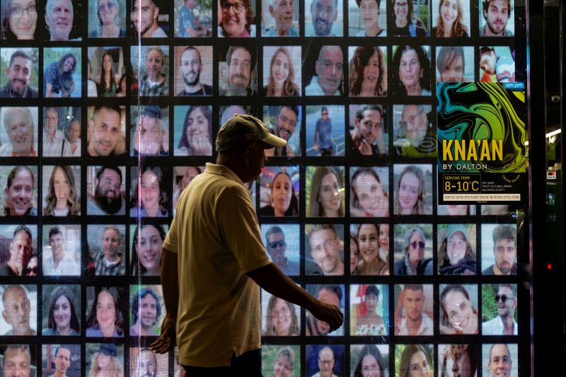 © Reuters. FILE PHOTO: A person walks past pictures of hostages kidnapped during the deadly October 7 attack by the Palestinian Islamist group Hamas from Gaza, projected on a screen, in Tel Aviv, Israel, May 31, 2024. REUTERS/Marko Djurica/File Photo