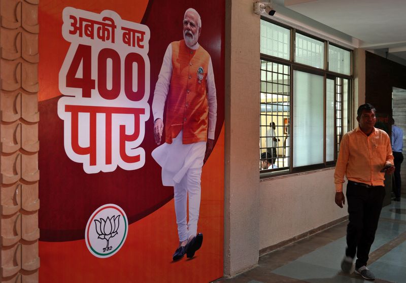 © Reuters. A supporter of the Bharatiya Janata Party (BJP) walks past a poster of Prime Minister Narendra Modi at its party's state headquarters in Gandhinagar, India, June 4, 2024. The poster reads, 