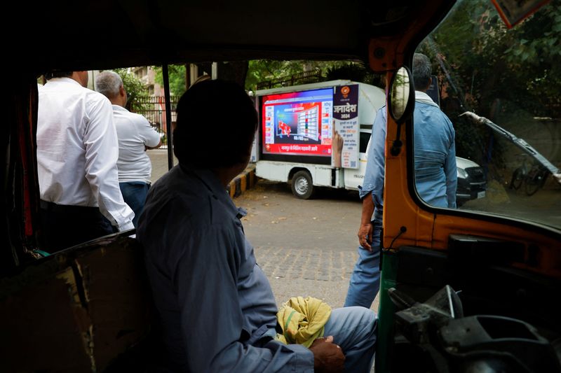 © Reuters. People watch the general election results on a screen installed on the side of a road, during the day of the general election results, in New Delhi, India, June 4, 2024. REUTERS/Adnan Abidi