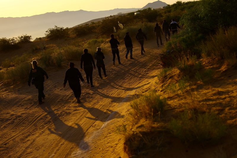 © Reuters. FILE PHOTO: U.S. Border Patrol agents detain migrants who attempted to cross the U.S.-Mexico border undetected, in an area outside Sunland Park desert, New Mexico, U.S., June 23 2023. REUTERS/Jose Luis Gonzalez/File Photo