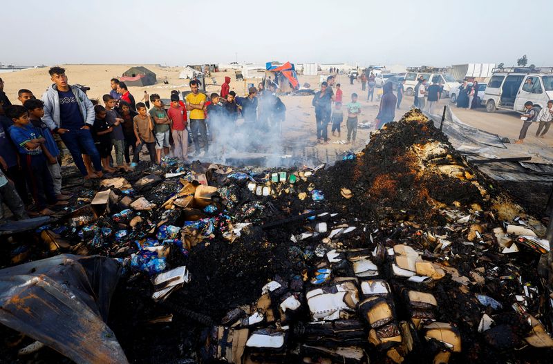 © Reuters. FILE PHOTO: Palestinians look at the damages while searching for food among burnt debris at the site of an Israeli strike on an area designated for displaced people, in Rafah in the southern Gaza Strip, May 27, 2024. REUTERS/Mohammed Salem/File Photo