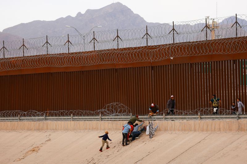 © Reuters. Migrants seeking asylum in the United States try to cross a razor wire fence deployed to inhibit their crossing into the U.S., as seen from Ciudad Juarez, Mexico, June 4, 2024. REUTERS/Jose Luis Gonzalez