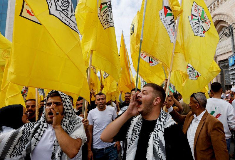 © Reuters. FILE PHOTO: People hold Fatah flags during a protest in support of the people of Gaza, as the conflict between Israel and Palestinian Islamist group Hamas continues, in Hebron, in the Israeli-occupied West Bank, October 27, 2023. REUTERS/Mussa Qawasma/File Photo