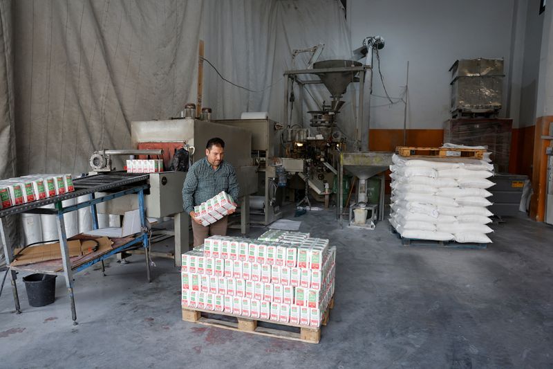 © Reuters. FILE PHOTO: A Palestinian worker loads bags of sugar in a warehouse, amid the ongoing conflict in Gaza between Israel and the Palestinian Islamist group Hamas, in Hebron, in the Israeli-occupied West Bank May 28, 2024. REUTERS/Mussa Qawasma/File Photo