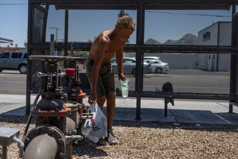 © Reuters. A homeless person refresh himself from water from a pipe line as temperatures are expected to soar above 110 degrees Fahrenheit (43.3 degrees Celsius) during the summer's first heat wave, in Phoenix, Arizona, U.S., June 6, 2024. REUTERS/Carlos Barria