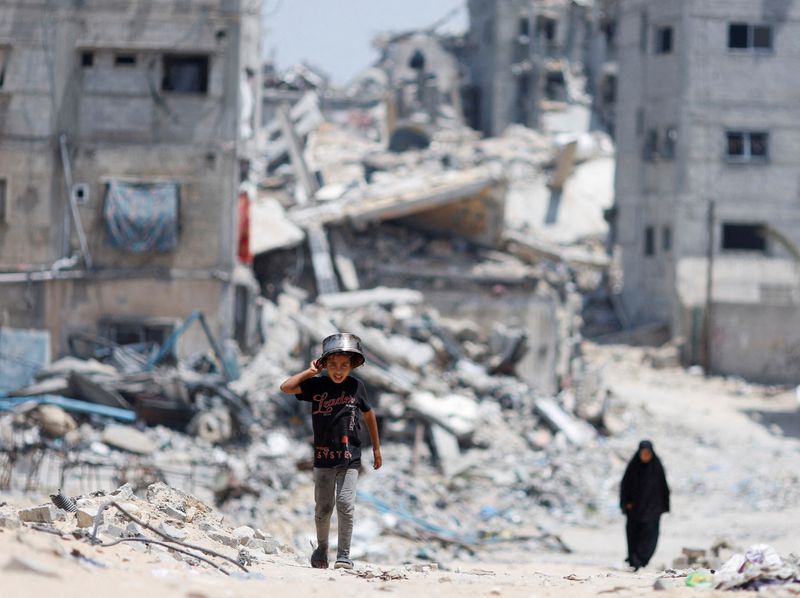 &copy; Reuters. Palestinians walk by houses which were destroyed in an Israeli strike, amid the ongoing conflict between Israel and Hamas, in Khan Younis, in the southern Gaza Strip, May 22, 2024. REUTERS/Mohammed Salem/File photo