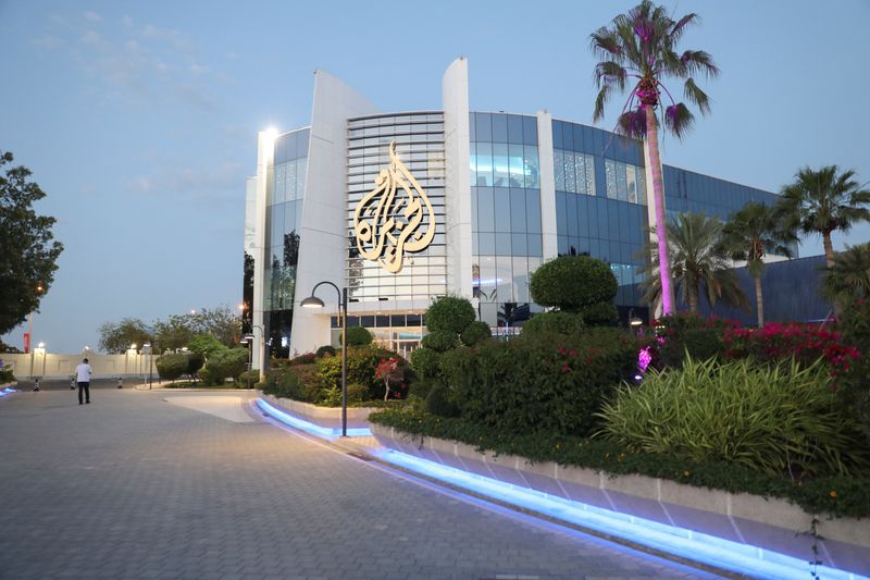 © Reuters. FILE PHOTO: A man walks near an Al Jazeera building in Doha, Qatar, May 5, 2024. REUTERS/Arafat Barbakh/File Photo