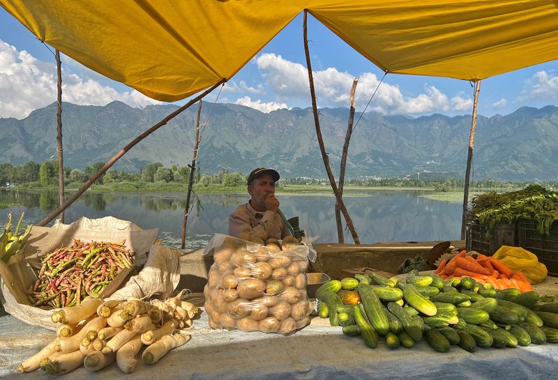 © Reuters. FILE PHOTO: A vendor selling vegetables smokes a hookah as he waits for customers alongside a road in Srinagar July 9, 2023. REUTERS/Altaf Hussain/File Photo