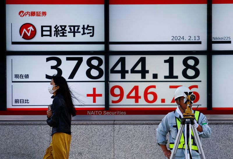 ©Reuters.  FILE PHOTO: Passersby pass in front of an electric screen displaying Japan's Nikkei stock average outside a brokerage in Tokyo, Japan, February 13, 2024. REUTERS/Issei Kato/file photo