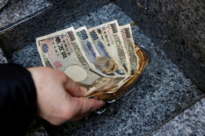 © Reuters. FILE PHOTO: A visitor washes Japanese yen banknotes and coins in water to pray for prosperity at Koami shrine in Tokyo's Nihonbashi business district, Japan, November 13, 2017. REUTERS/Toru Hanai/File Photo